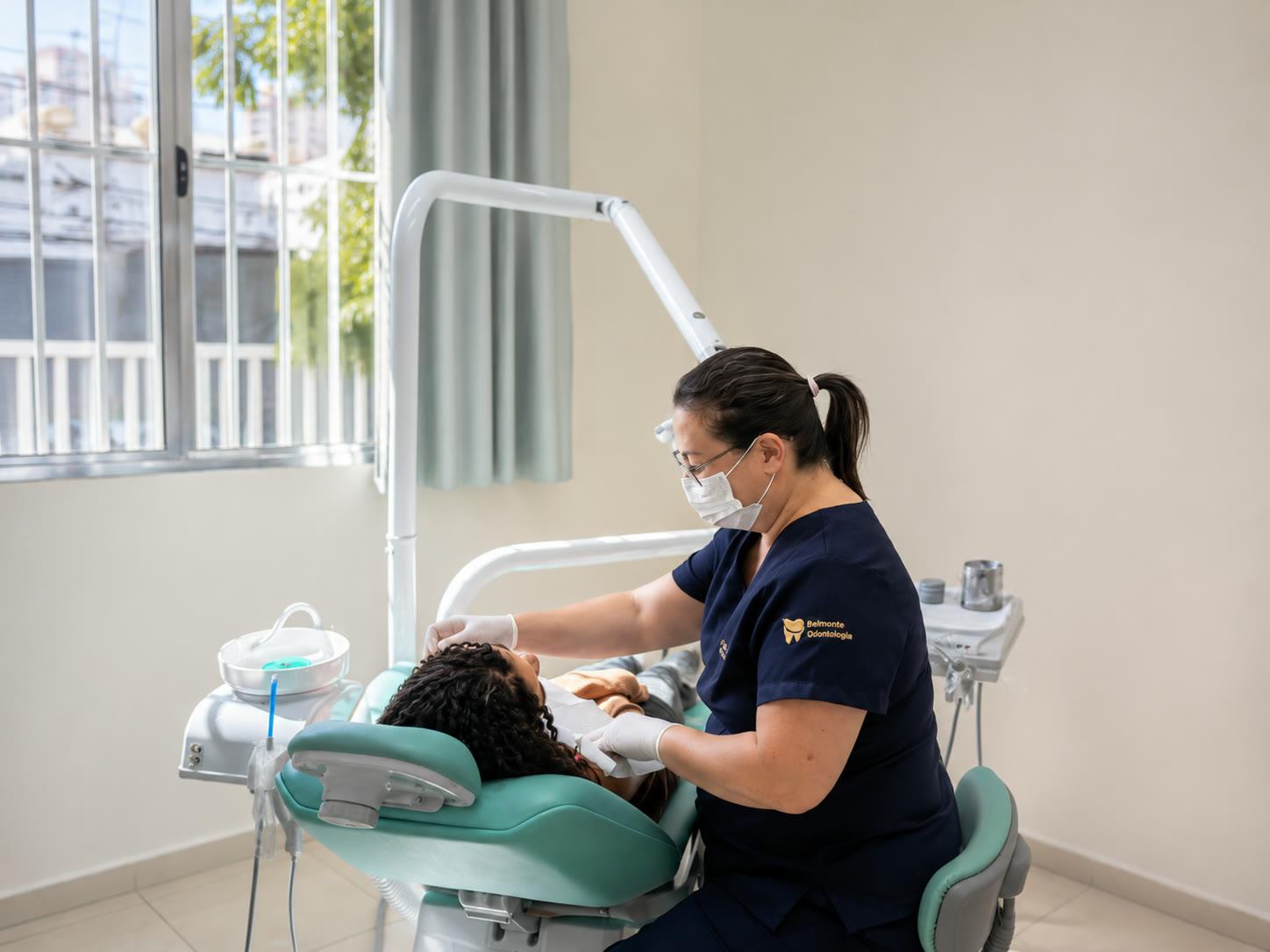 Dentista da Belmonte Odontologia atendendo uma paciente em consultório